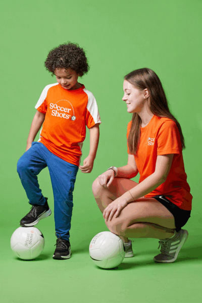 Soccer Shots coach instructing boy with soccer ball
